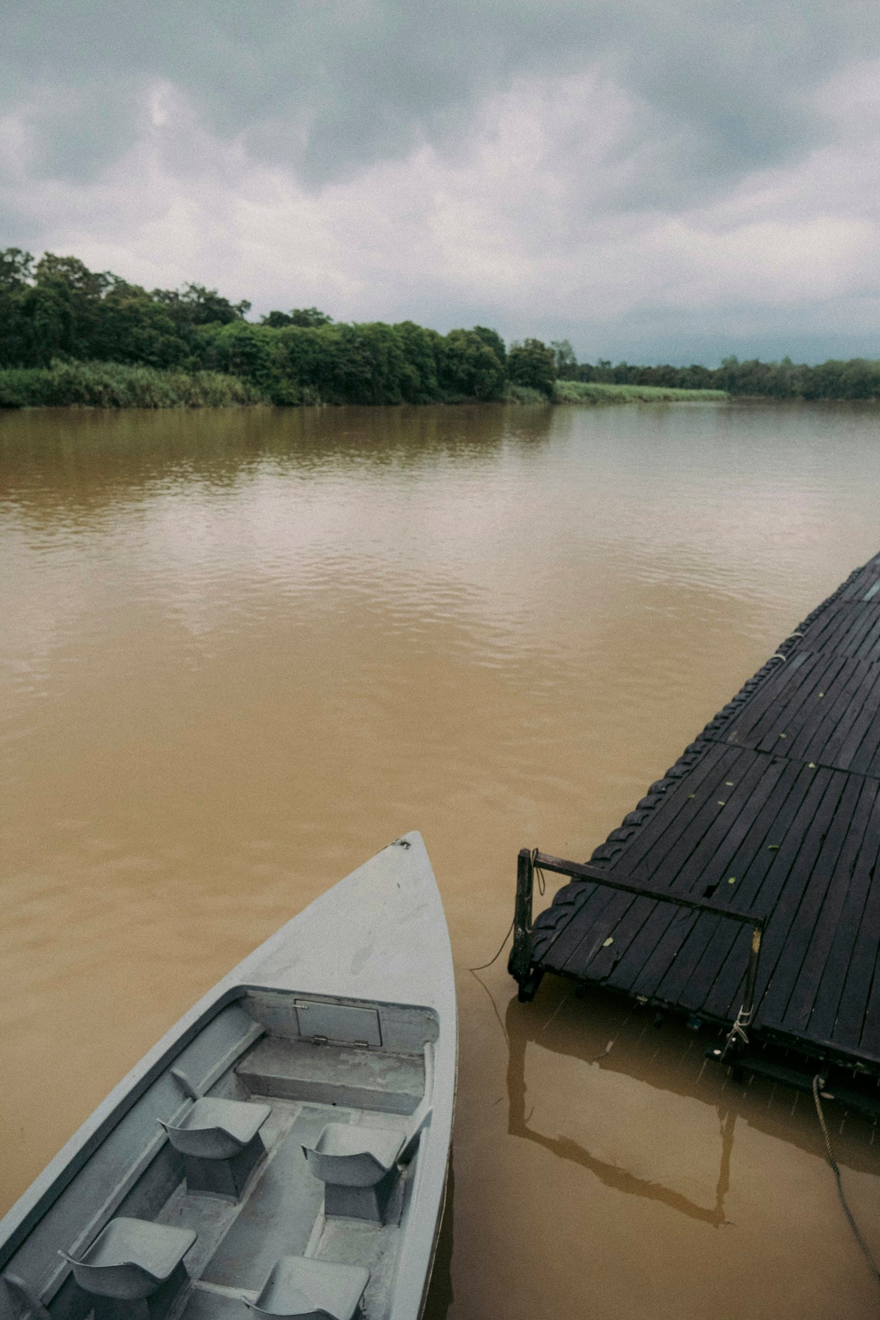 Ujung perahu di samping dermaga kayu di sungai cokelat