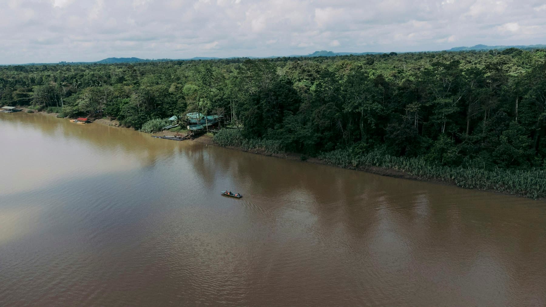Perahu menyusuri sungai lebar di tengah hutan Kalimantan